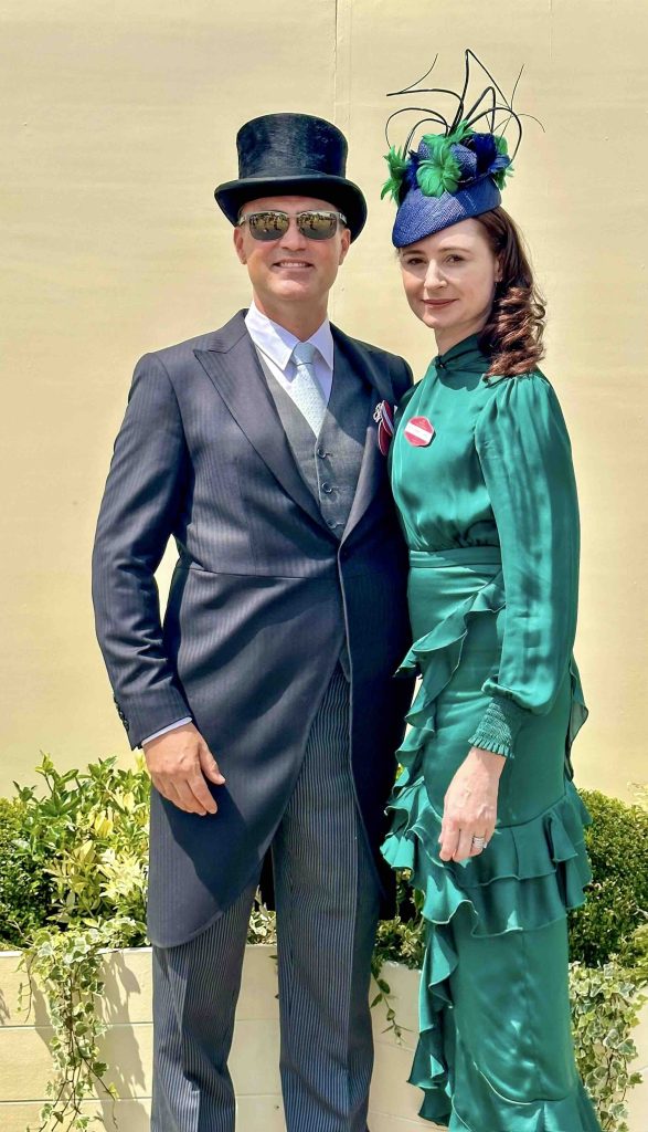 A man in a top hat and a woman in a green dress stand together outdoors. | Sarah Ross Millinery