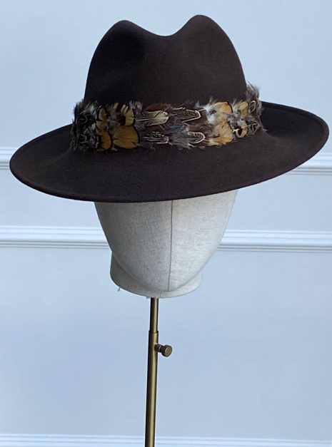 A brown felt hat with a decorative feather band displayed on a mannequin head. | Sarah Ross Millinery