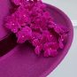 Close-up of a pink felt hat with a cluster of fabric flowers on the brim. | Sarah Ross Millinery