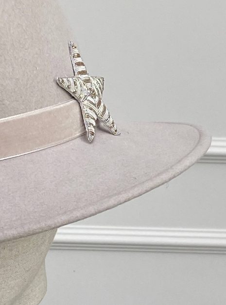 IMG_1937 A beige hat with a wide brim features a silver and black star-shaped brooch on the band. | Sarah Ross Millinery