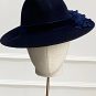 A black hat with a wide brim and dark floral details on the side, displayed on a mannequin head. | Sarah Ross Millinery