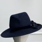 A dark blue wide-brimmed hat displayed on a mannequin head, featuring a subtle floral decoration on one side. | Sarah Ross Millinery
